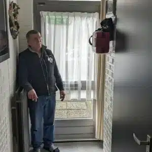 Mann und Frau zeigen montiertes AED in Wohnungsgang