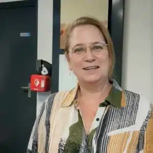 Frau steht vor montiertem AED-Gerät im Eingangsbereich