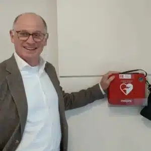 Mann mit Brille präsentiert montierten Defibrillator
