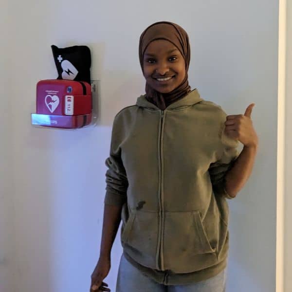 Person zeigt auf Wandhalterung mit Defibrillator